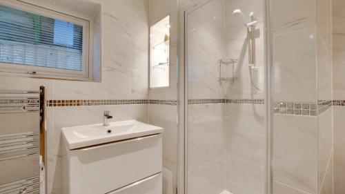 baño blanco con ducha y lavamanos en Langland Corner Lodge, en Newton