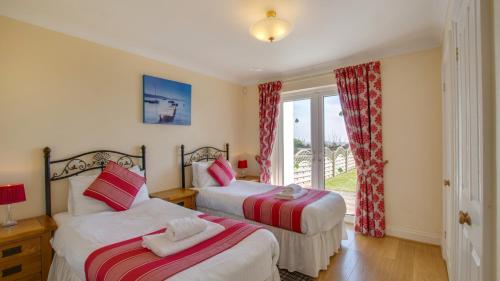 2 Betten in einem Zimmer mit Fenster in der Unterkunft Fennel Cottage in Port-Eynon