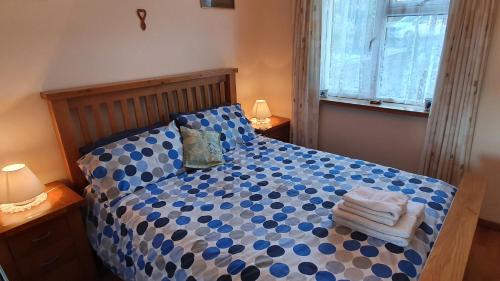 a bedroom with a blue and white bed with two lamps at Granny Shells in The Mumbles