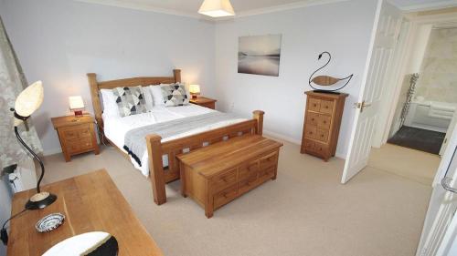a bedroom with a bed with wooden furniture and a desk at Honeycomb Cottage in The Mumbles