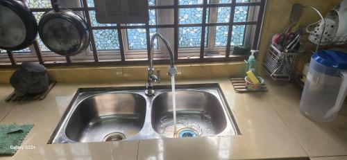 a kitchen sink with water coming out of it at Homestay Hassani in Kepala Batas