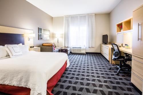 a hotel room with a large bed and a desk at TownePlace Suites by Marriott Gilford in Gilford