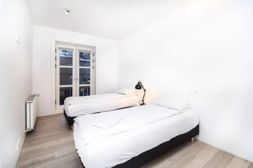 two beds in a white room with a window at City Point Reykjavik - Luxury Apartments - Surtsey in Reykjavík