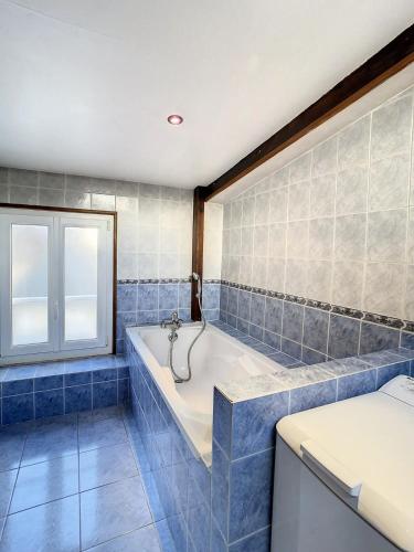 a blue tiled bathroom with a tub and a window at Charmant triplex centre-ville de Chantilly in Chantilly