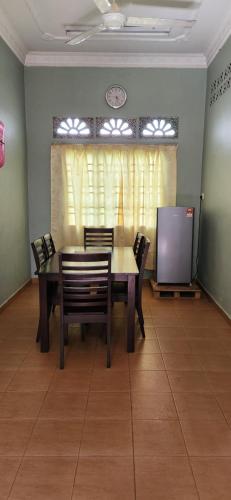 comedor con mesa, sillas y TV en Homestay Hassani en Kepala Batas