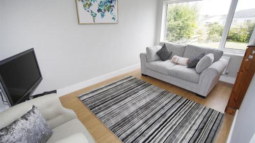 a living room with a couch and a tv at Trelau in Parkmill