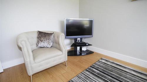 a living room with a chair and a television at Trelau in Parkmill