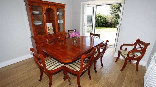 a wooden dining room table with chairs and a cabinet at Trelau in Parkmill