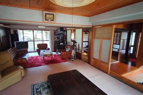 sala de estar con sofá y mesa en 里山アウトドアフィールド・古民家コテージとろせ, en Gujō