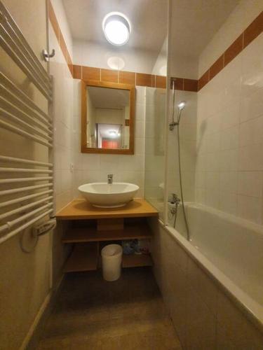 une salle de bain avec un lavabo, un miroir et une baignoire dans l'établissement Chez Angélique et Romain - Appartement agréable au pied des pistes, à La Plagne