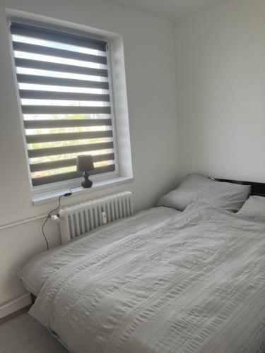 a white bed in a bedroom with a window at Horizont-Szilvás Apartman in Komló