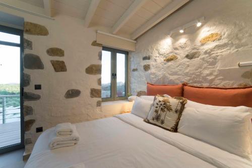 ein Schlafzimmer mit einem großen Bett und einer Steinmauer in der Unterkunft Afentiko Pigadi in Methoni