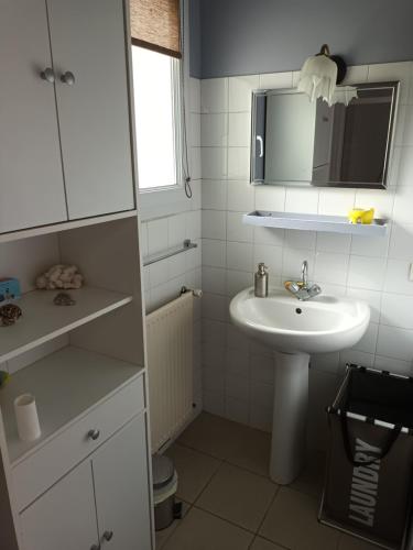 a white bathroom with a sink and a mirror at Vaiana in Beauvoir-sur-Mer