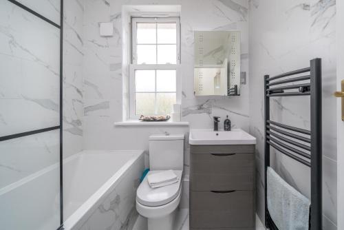 een witte badkamer met een toilet en een wastafel bij Elegant 3 Bedroom Retreat Minutes from Canary Wharf in Londen
