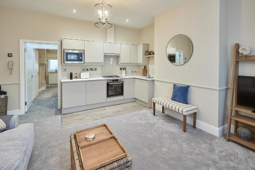 a kitchen with white cabinets and a living room at Host & Stay - Normanby Terrace Apartments in Whitby