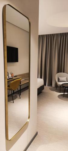 a mirror in a hotel room with a bed and a desk at Silken Ciudad Gijón in Gijón