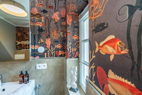 Gemütliche Wohnung unter Reet mit Pool und Sauna in Keitum في كيتوم: حمام به لوحة جدارية للأسماك على الحائط