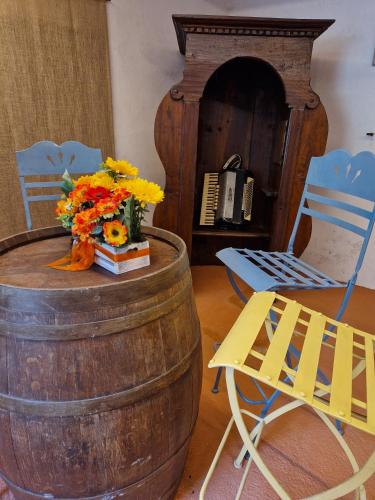 a wooden barrel with a vase of flowers and a chair at Mister Barolo Apartments Langhe in Novello