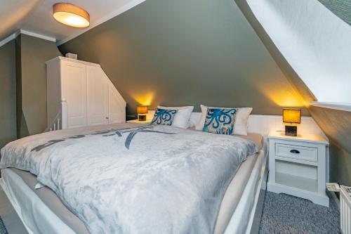 a bedroom with a large bed with blue pillows at Gemütliche Wohnung unter Reet mit Pool und Sauna in Keitum in Keitum