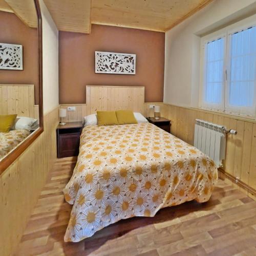 a bedroom with a bed with a yellow and white bedspread at Apartamentos La Capitana in Luarca