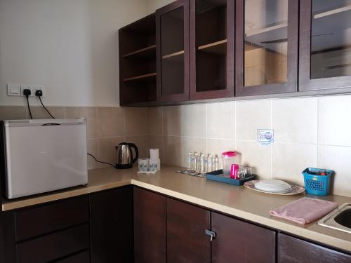 a kitchen with brown cabinets and a white refrigerator at Gold Coast Morib Rerost By Sweetime in Kampong Tanjong Pechah
