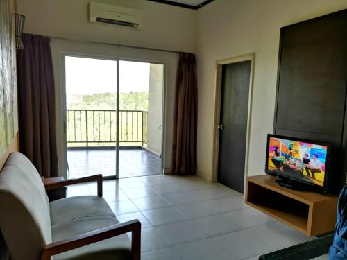 a living room with a couch and a television and a balcony at Gold Coast Morib Rerost By Sweetime in Kampong Tanjong Pechah