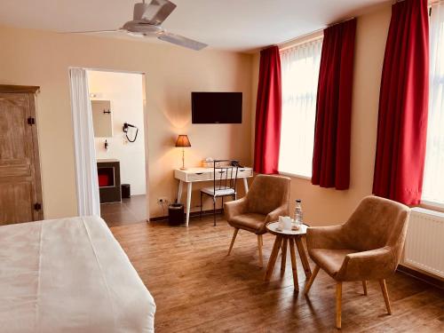 a bedroom with a bed and two chairs and a table at Hotel Het Heilig Genot in Westvleteren