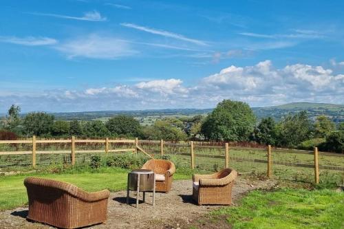 three wicker chairs and a table in a field at Celaeron Glamping in Aberaeron