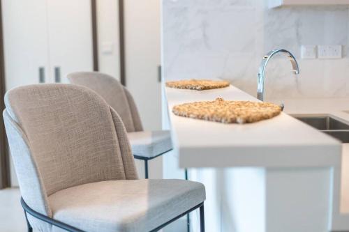 The bright One Residence by Suiteable Interiors في دبي: مطبخ فيه كرسيين ومغسلة عليها اكل