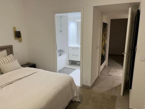 biała sypialnia z łóżkiem i łazienką w obiekcie Horizon Bay - Pool - Fitness Room - Terrace w Cannes