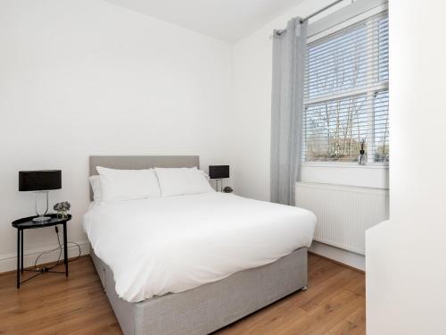 a white bedroom with a large bed and a window at Pass the Keys Serenity in the Suburbs - Modern 2BR Apartment in Liverpool