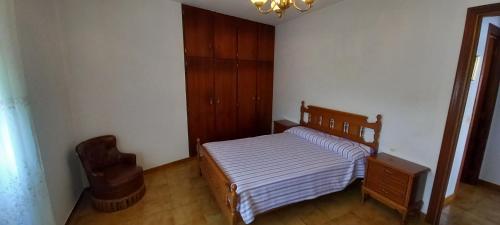een kleine slaapkamer met een bed en een stoel bij Pensión Baires in O Coto