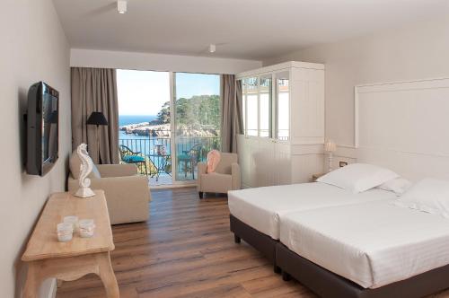 a hotel room with a bed and a view of the ocean at Hotel Aigua Blava in Begur