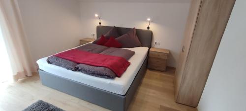 1 dormitorio con 1 cama con almohadas rojas y grises en Haus Alpenrose, en Sankt Leonhard im Pitztal