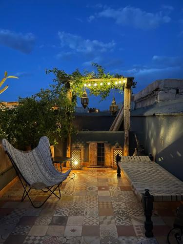 a patio with a chair and a pergola with lights at Riad Chocolat in Marrakech