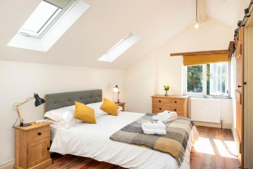 1 dormitorio con 1 cama con sábanas blancas y almohadas amarillas en North Beer Cottage, en Launceston