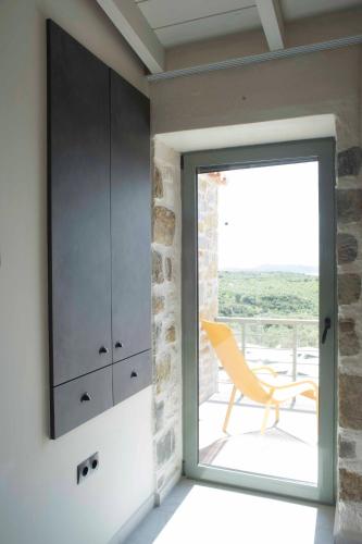 a sliding glass door leading to a patio with a chair at Afentiko Pigadi in Methoni