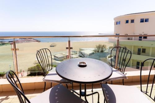a table and chairs on a balcony with a view of the beach at Rezident Eforie Nord in Eforie Nord