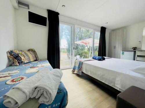 1 Schlafzimmer mit 2 Betten und einem großen Fenster in der Unterkunft Agricampeggio Ippocampo in La Cinquantina