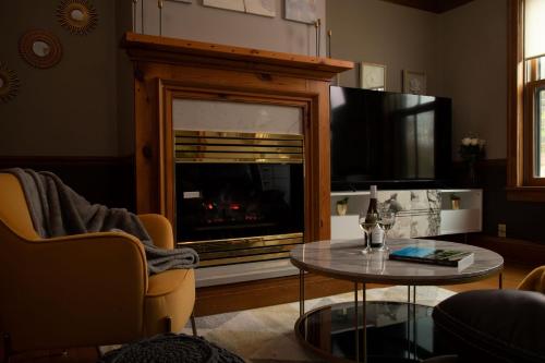 a living room with a fireplace with a tv and a table at Riverboat Suites in Galena