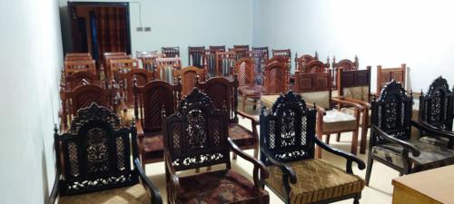 a row of wooden chairs in a room at Hotel Shelton Palace in Multan