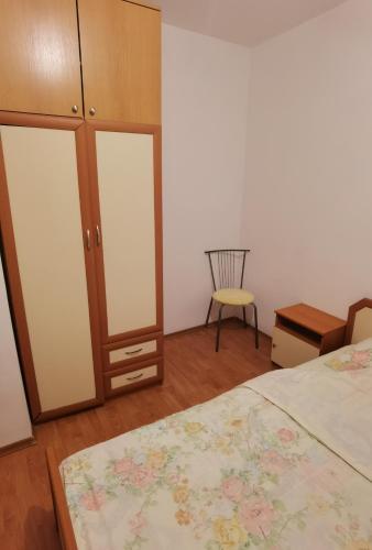 een slaapkamer met een bed, een kast en een stoel bij Гарсониера in Stara Zagora