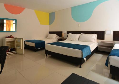 1 dormitorio con 2 camas con pintura colorida en las paredes en Hotel San Fermin Pereira, en Pereira