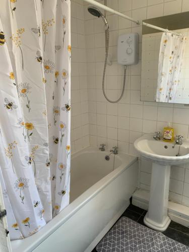 a bathroom with a tub and a sink and a shower curtain at 18 Main Street in St Bees