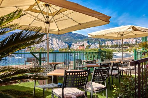 a patio with tables and chairs and umbrellas at Beach Hotel Rosa in Malcesine