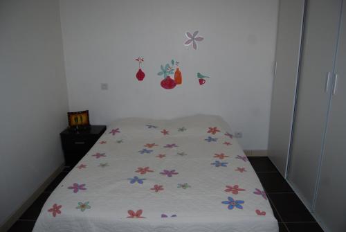 un lit avec une couverture blanche avec des fleurs colorées dessus dans l'établissement Villa lilousa, à Le Soler