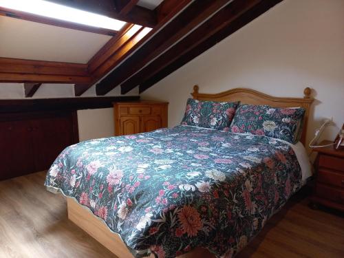 1 dormitorio con 1 cama con colcha de flores en La casuca del sol, en Potes