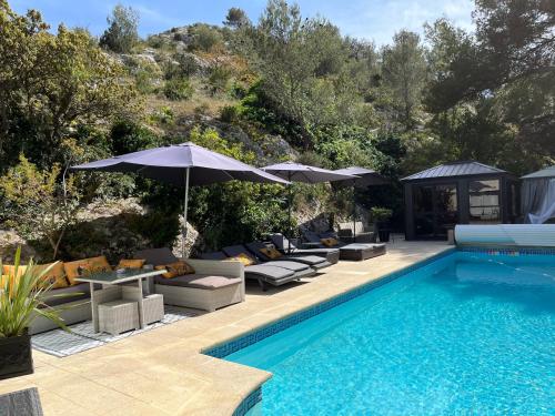 a swimming pool with couches and umbrellas next to a swimming pool at Gîte des Estelles "Alixia" in Cavaillon