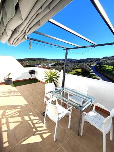 a patio with a glass table and white chairs at La Martela de Segura dúplex rural piscina in Segura de León
