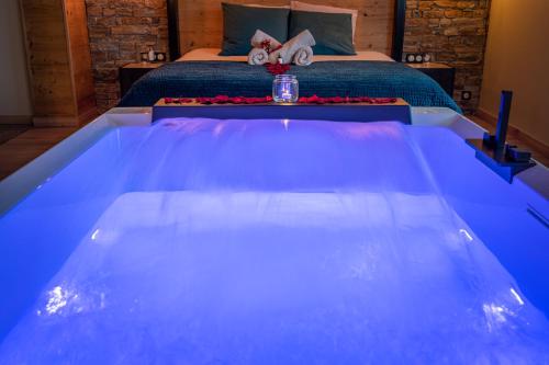 Cette chambre comprend un grand lit et une baignoire bleue. dans l'établissement Love industrie & spa - Suite Romantique en Alsace - Terrasse et garage, à Bischoffsheim